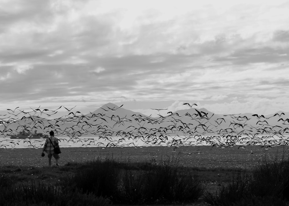 grayscale photo of person standing near fence