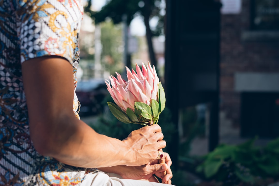 woman in white and red floral dress holding pink tulip