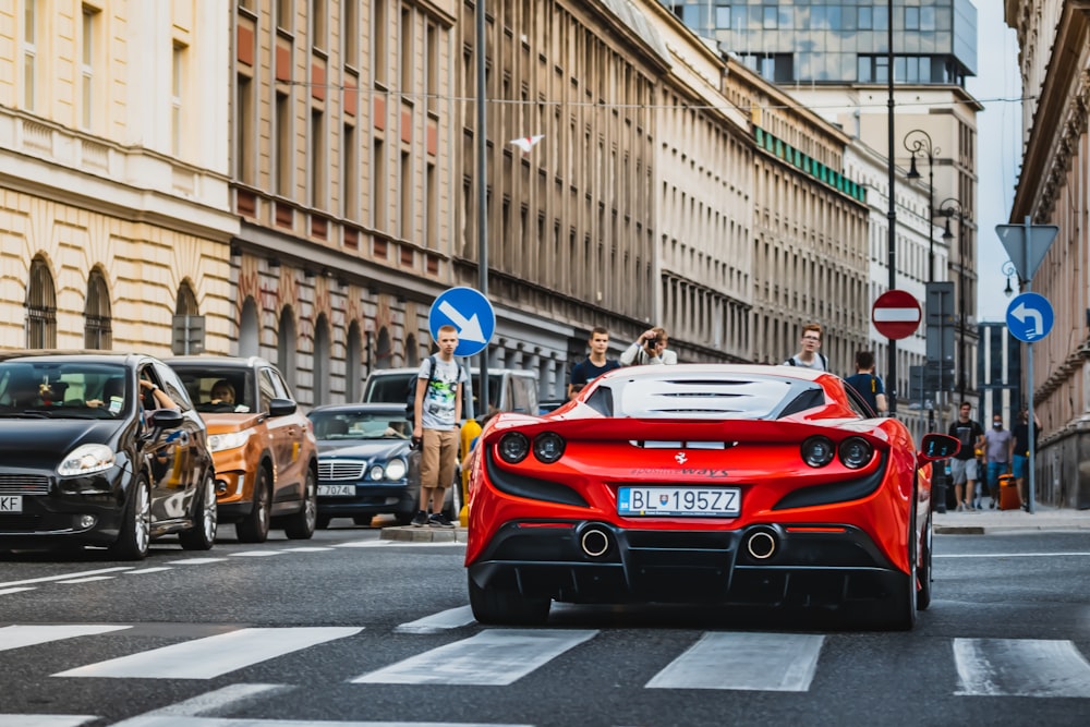 a red sports car driving down a city street