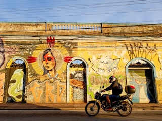 man in black jacket riding motorcycle near graffiti wall during daytime