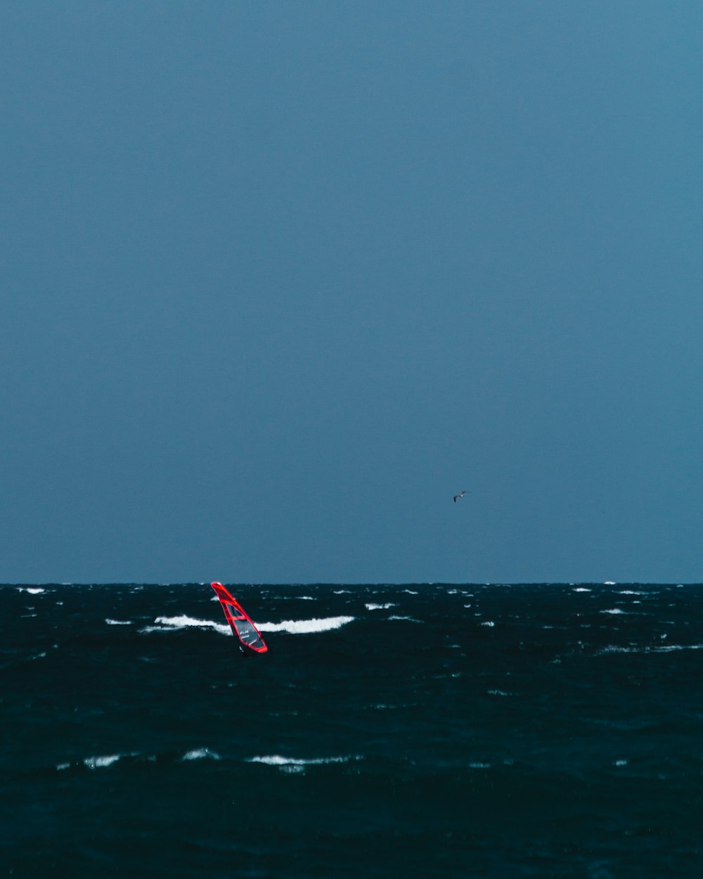 red and white flag on body of water during daytime