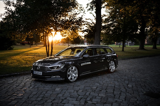A sleek black car parked in front of a cozy home at sunset.