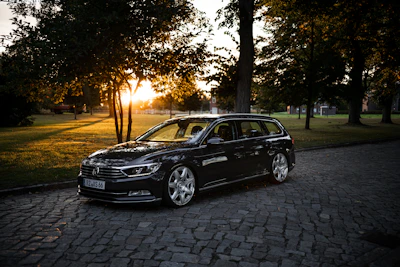 A sleek black electric taxi parked elegantly outside a charming wedding venue at sunset.