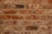 A symmetrical arrangement of unevenly colored red and brown bricks with visible mortar lines. Each brick varies slightly in texture and shade, suggesting handmade or rustic characteristics.