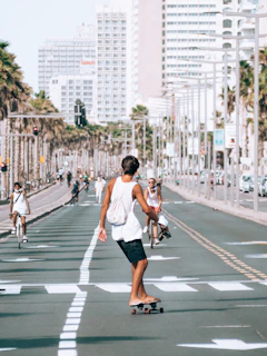A young person skateboarding down a sunlit urban street wearing a loose graphic tee from type of pose.
