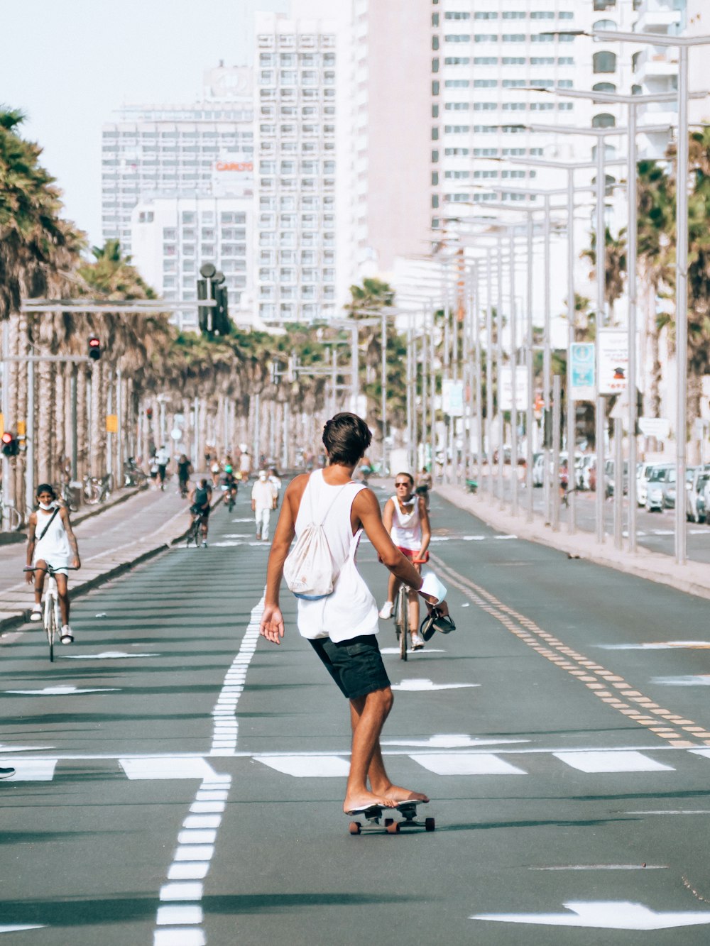 man in white tank top and black shorts running on pedestrian lane during daytime