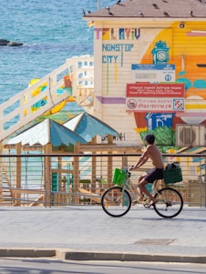 man in green shirt riding on bicycle near body of water during daytime