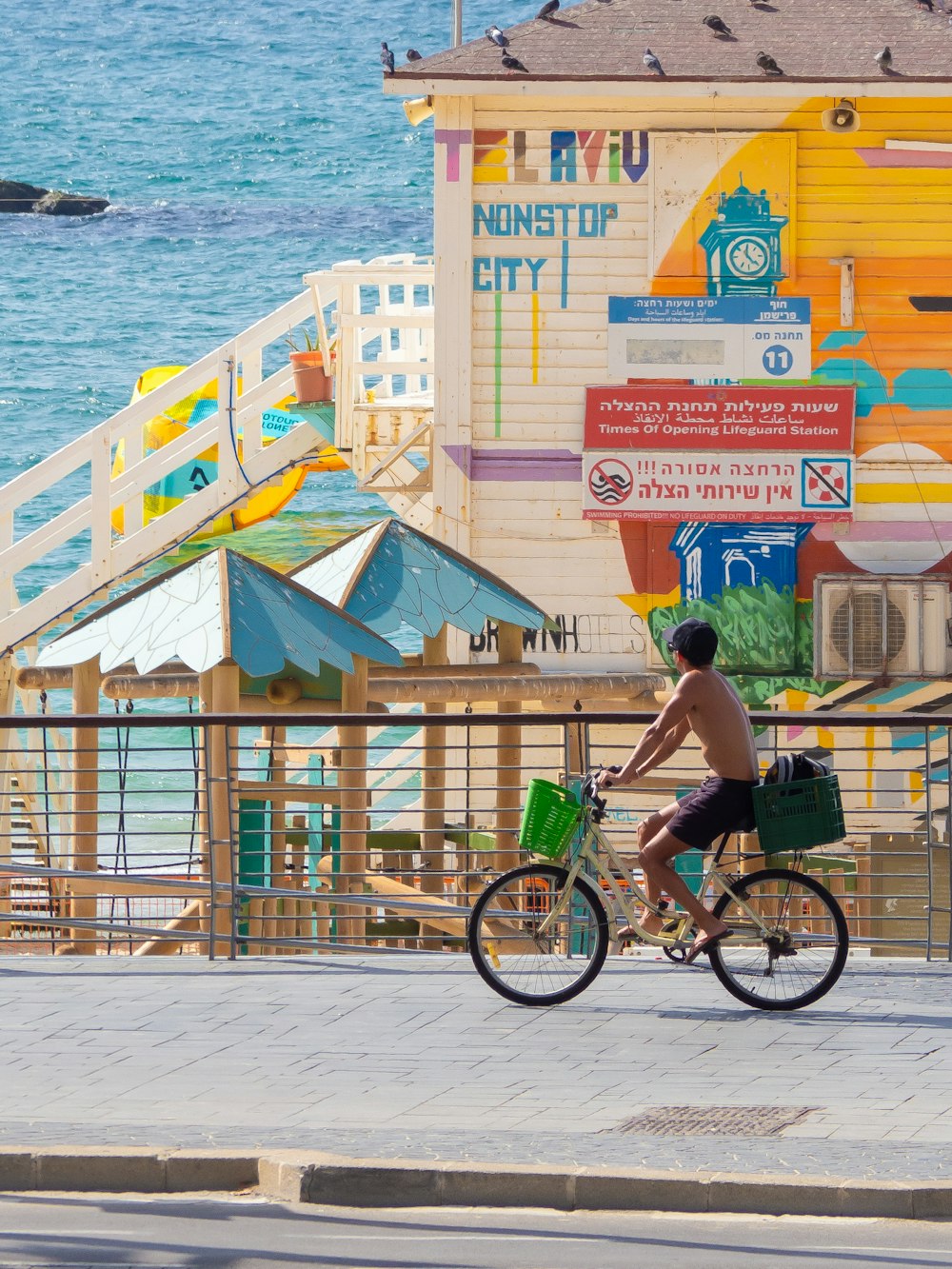 man in green shirt riding on bicycle near body of water during daytime