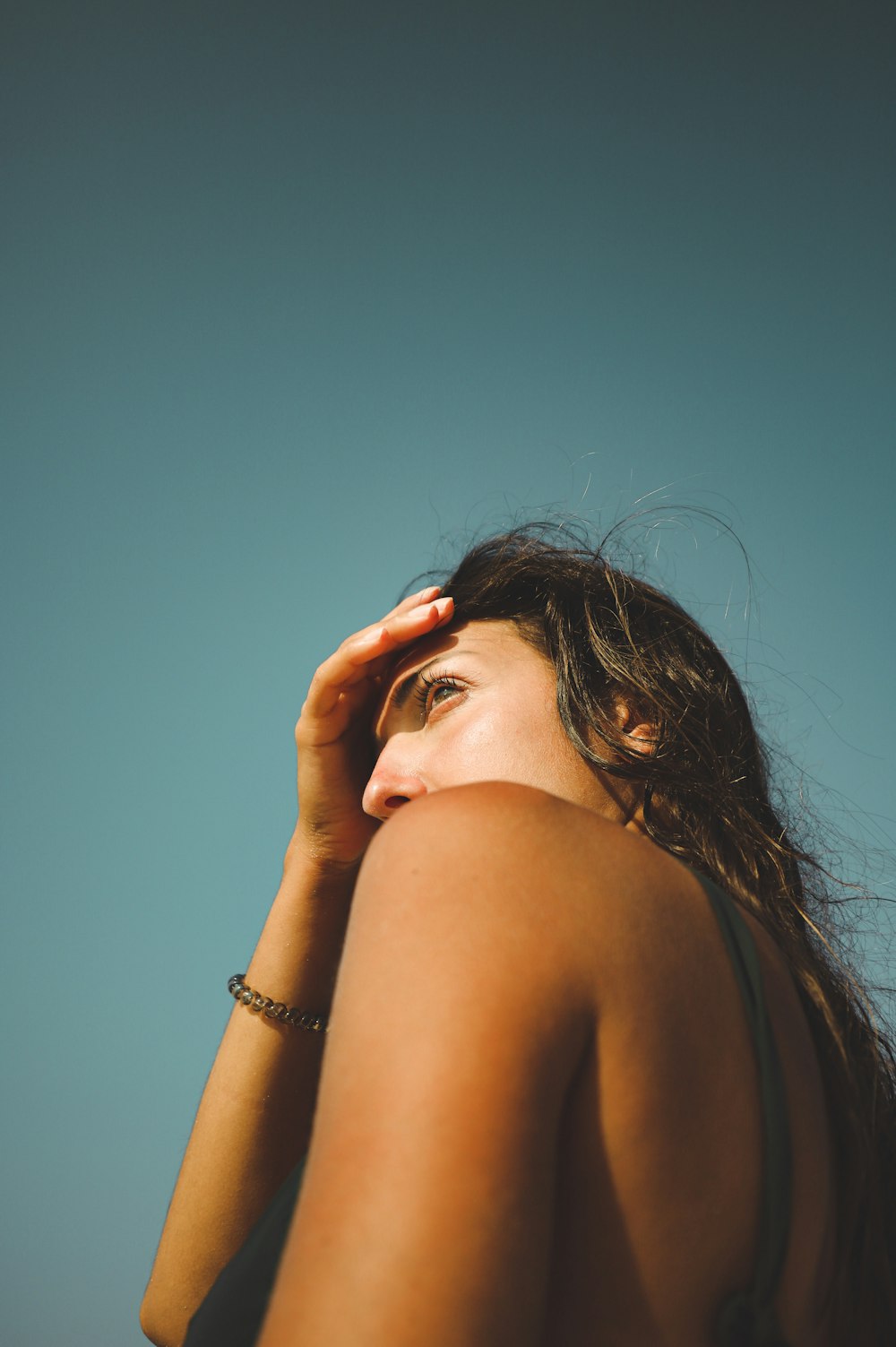 woman in silver bracelet covering her face with her hand