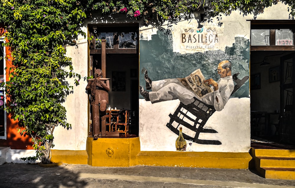 homem na camisa social branca sentado no banco ao lado da parede com grafite