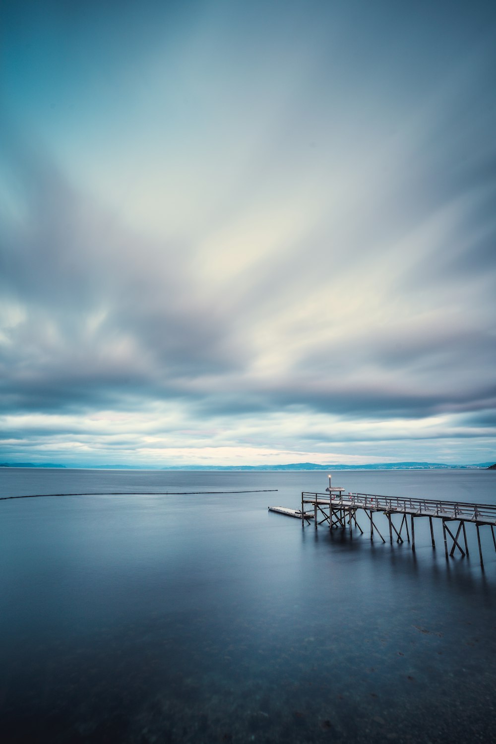 black metal railings on sea under white clouds and blue sky during daytime