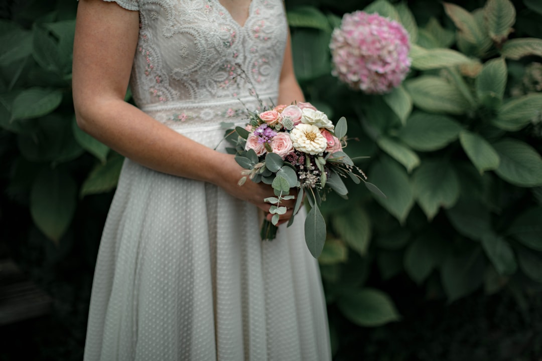 woman in white floral wedding dress holding bouquet of flowers