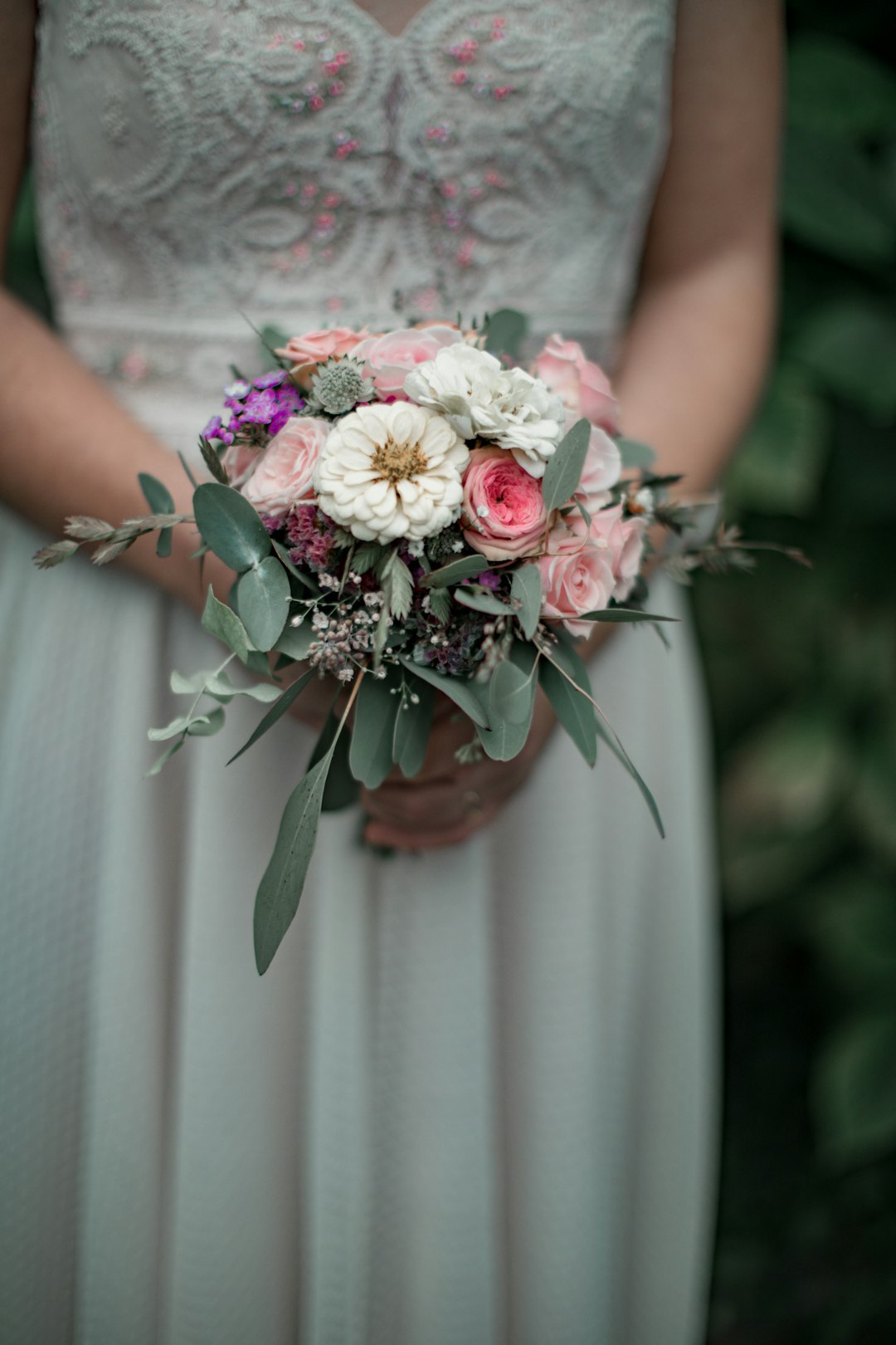 woman in white floral dress holding pink and white flower bouquet