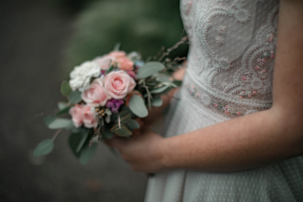 woman in white lace dress holding red and white rose bouquet