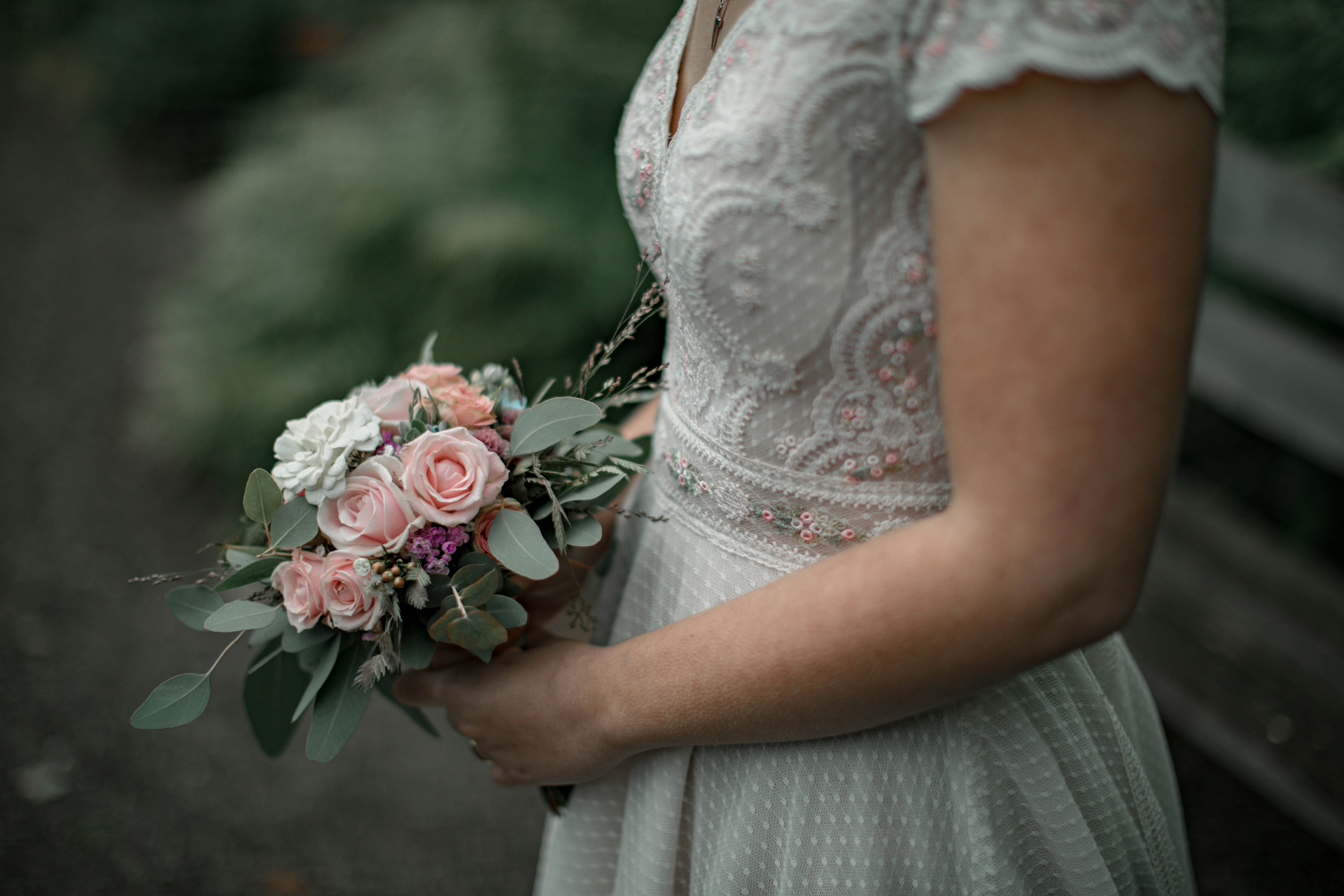 woman in white lace dress holding bouquet of flowers