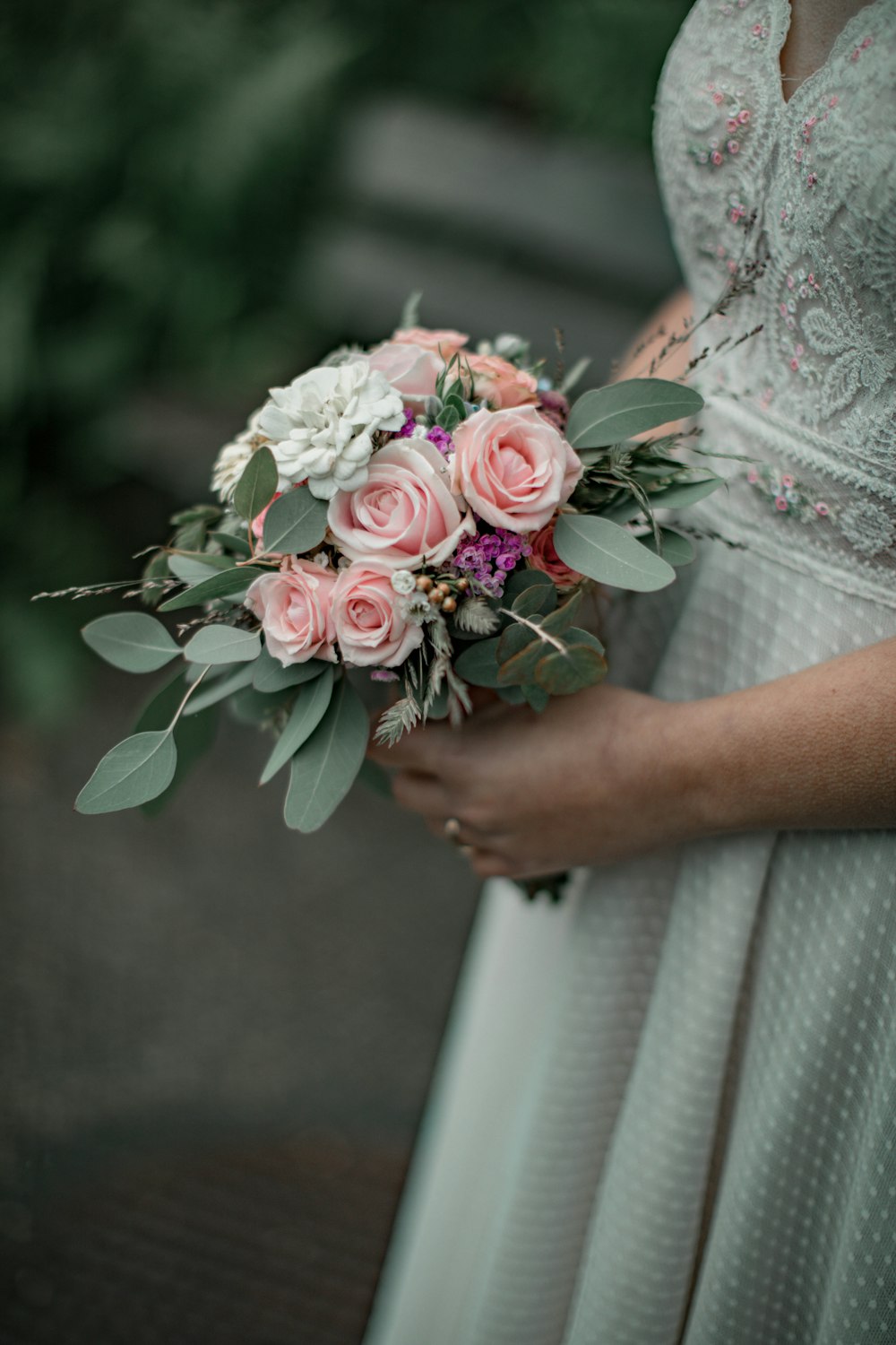 woman in white floral dress holding bouquet of flowers