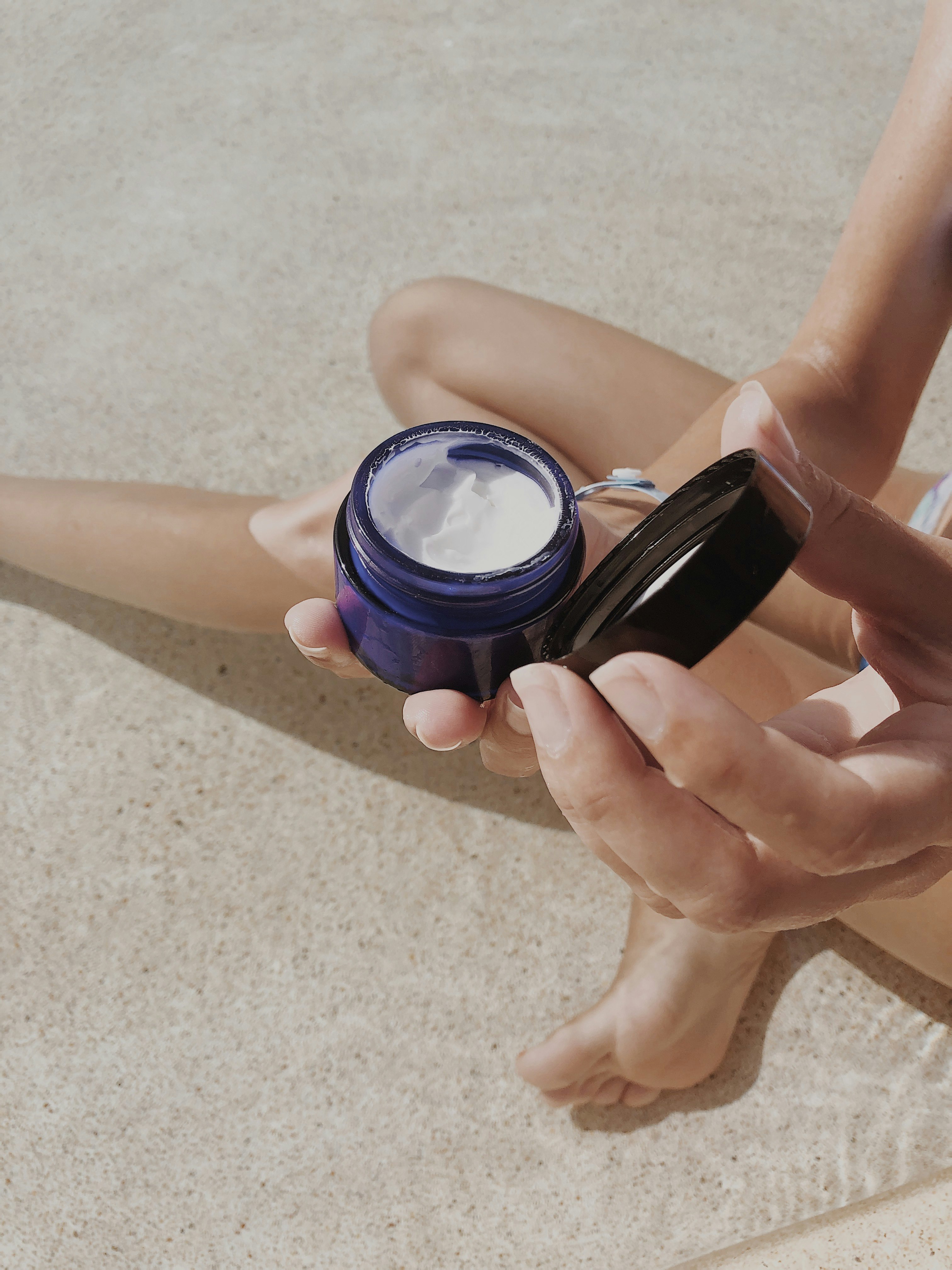 person holding blue round plastic container