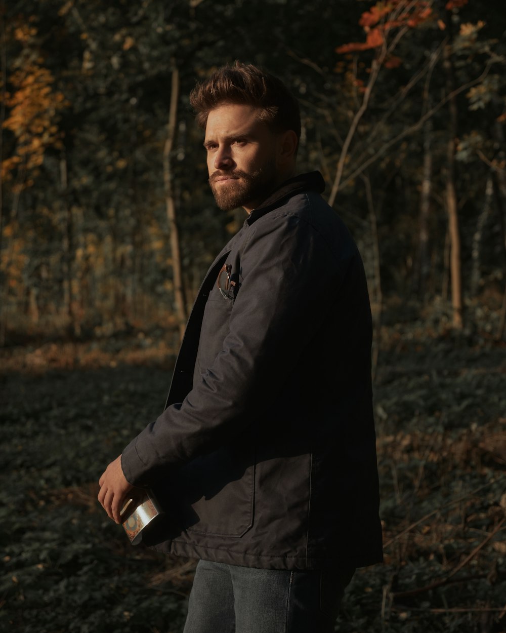 man in black jacket standing on forest during daytime