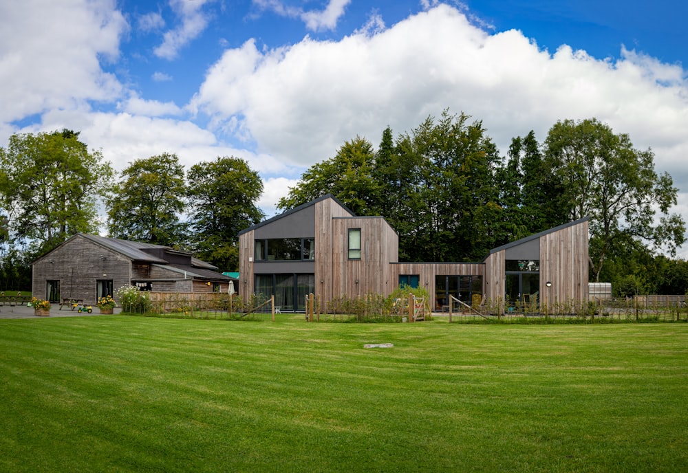 brown wooden house near green trees under white clouds during daytime