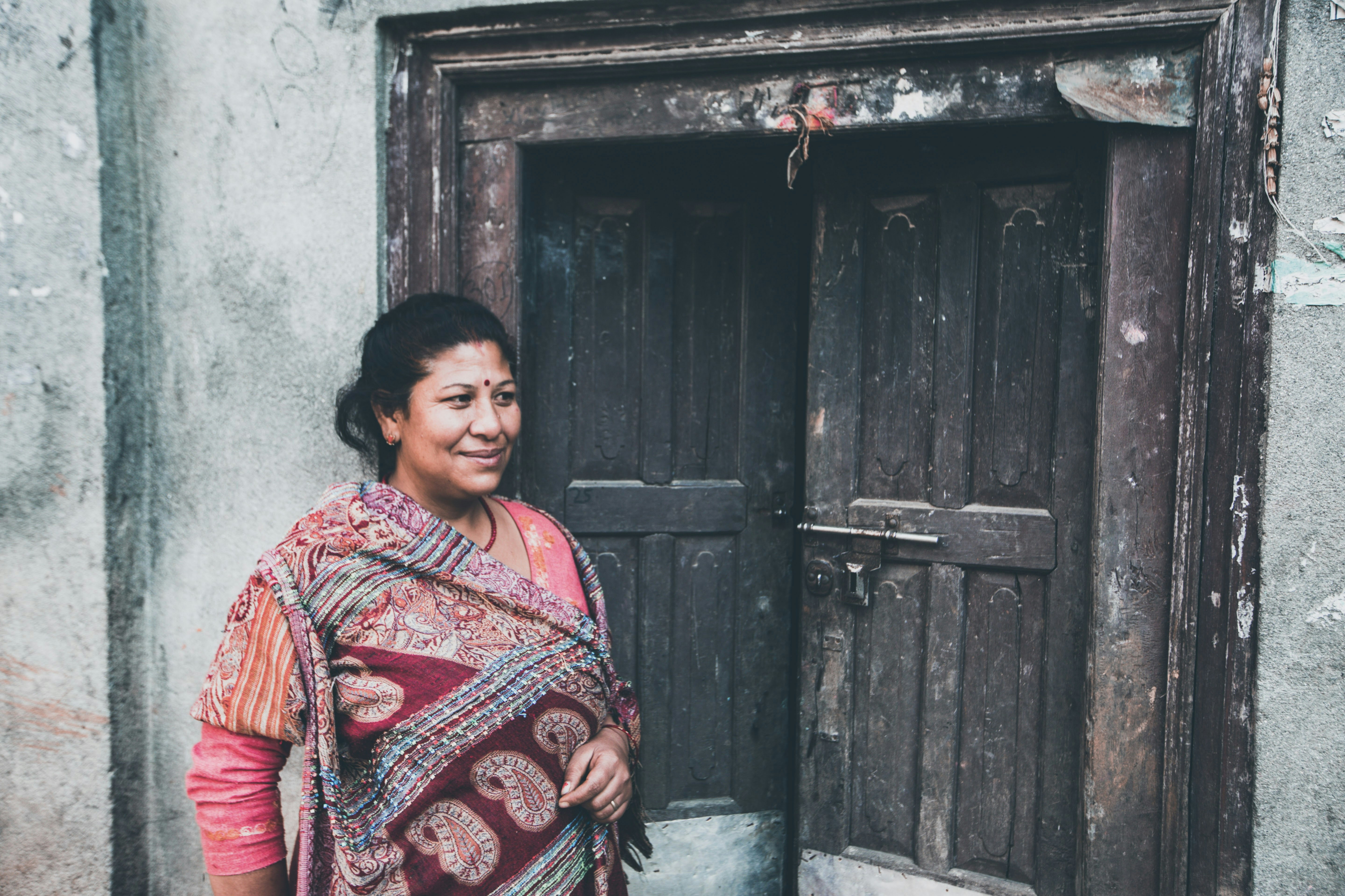 woman in red and white long sleeve dress standing beside brown wooden door