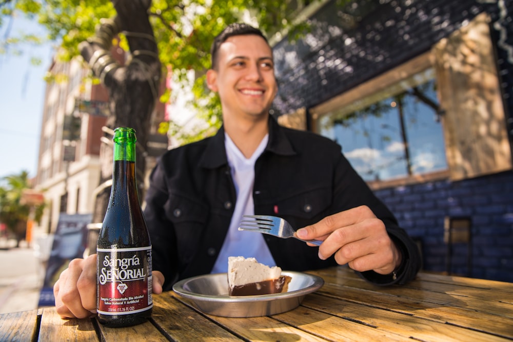 man in black blazer holding coca cola bottle