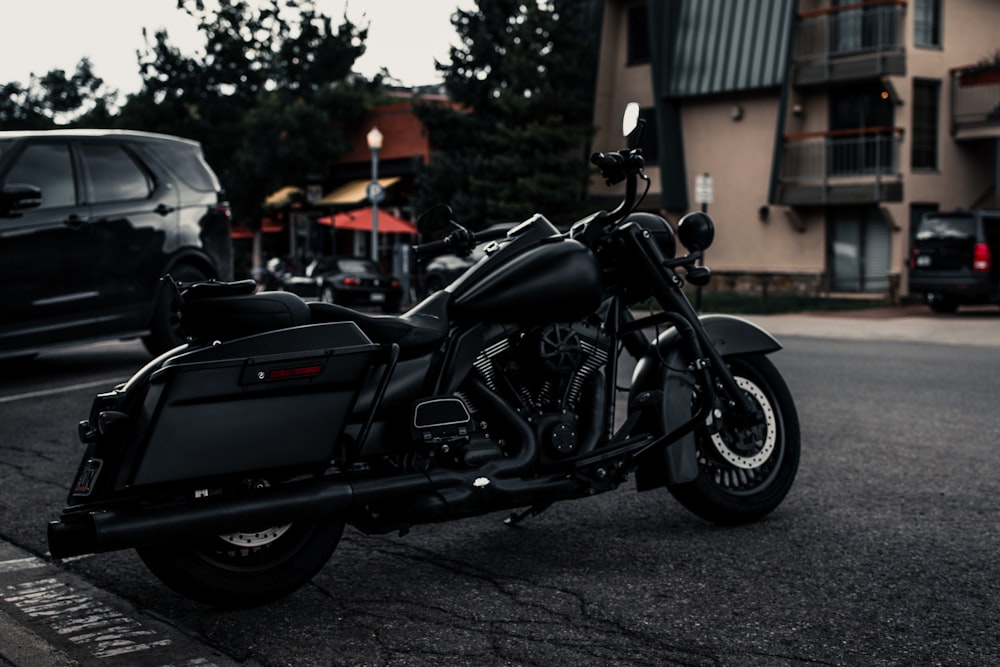 black and silver cruiser motorcycle parked on gray asphalt road during daytime