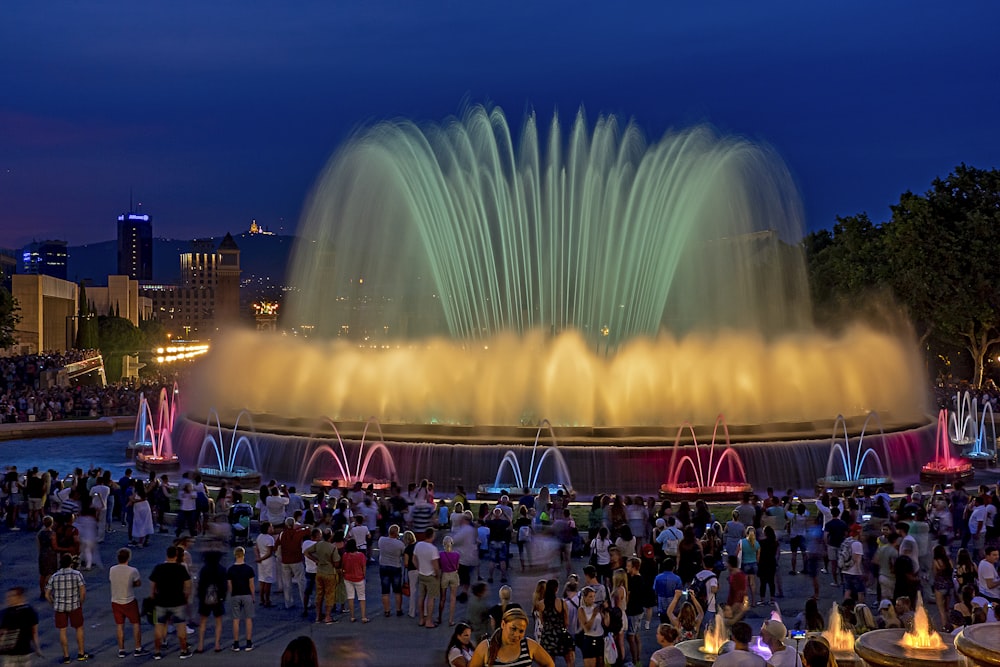 personnes debout près de la fontaine pendant la nuit