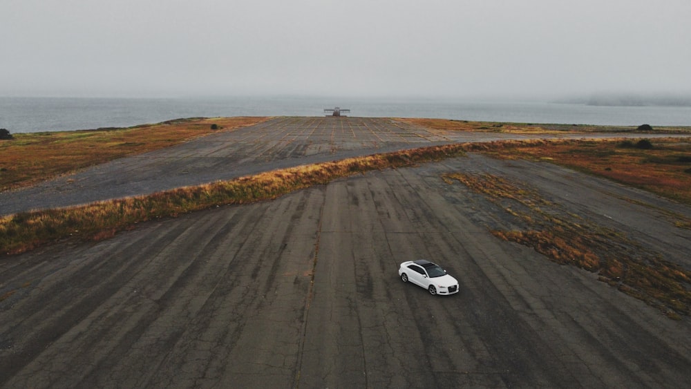 white coupe on gray asphalt road during daytime