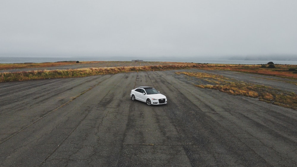 white coupe on gray asphalt road during daytime