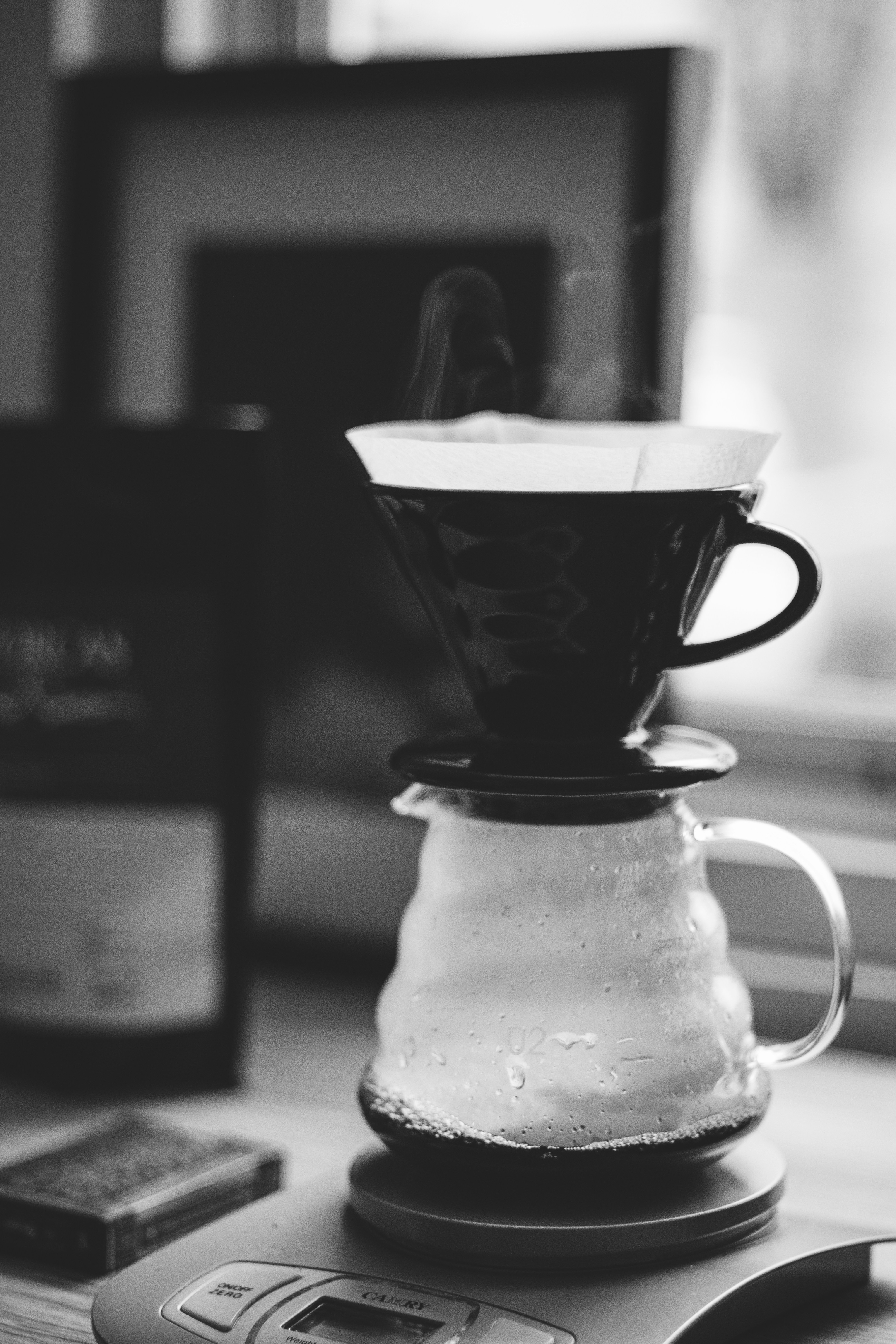 grayscale photo of white and black ceramic mug on glass jar