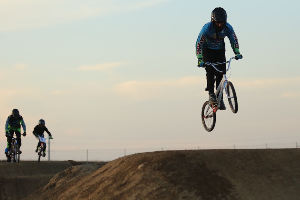 man in blue jacket riding bicycle on brown hill during daytime