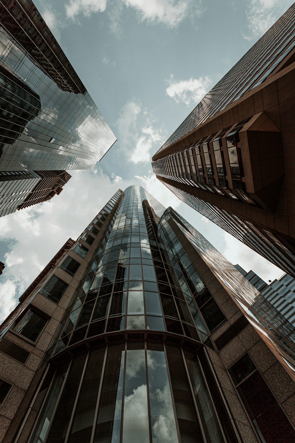 worms eye view of brown concrete building under blue and white sunny cloudy sky during