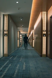 man in black jacket walking on hallway