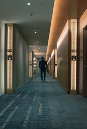 man in black jacket walking on hallway