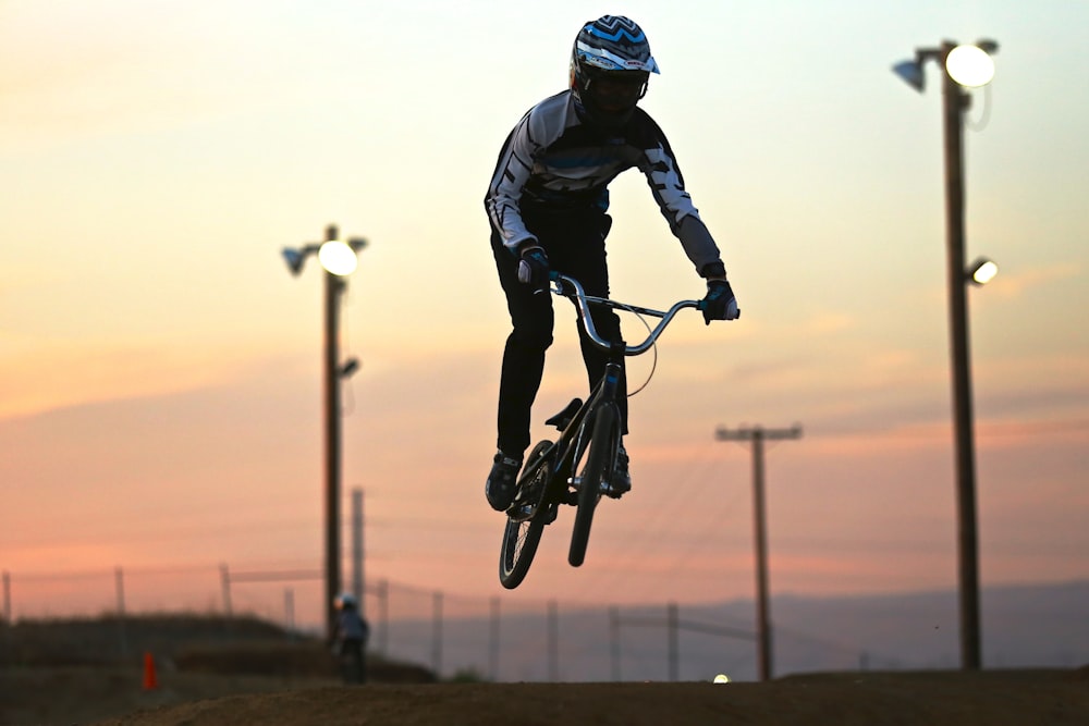 A man jumping in the air on his BMX bike at sunset