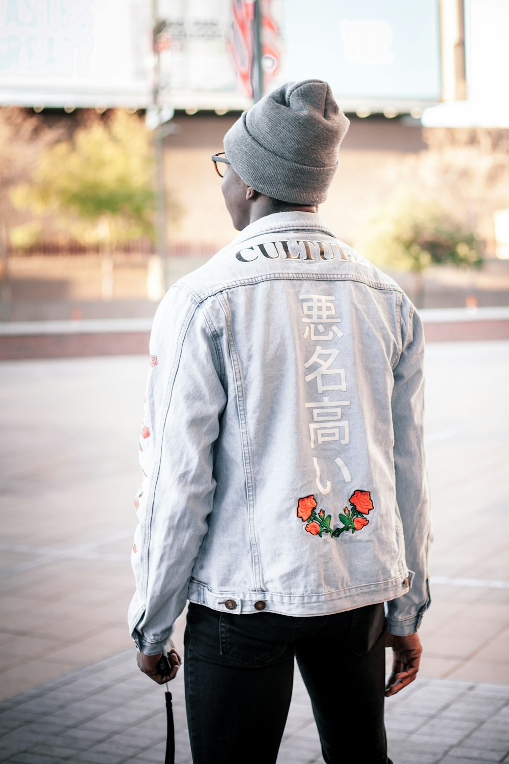 person in gray and red floral jacket and gray knit cap standing on road during daytime