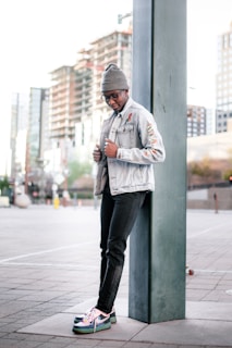 A casual city scene with a person wearing a denim jacket decorated with several Disney pins from urbanpincraft