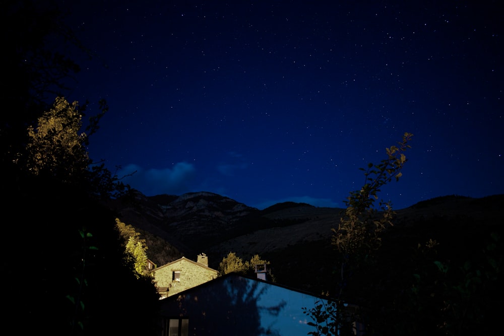 white and brown house near green trees under blue sky during night time