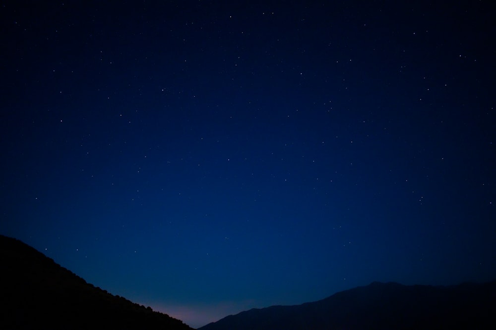 silhouette of mountain under blue sky during night time