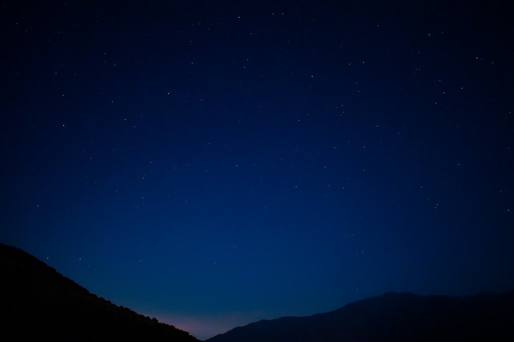 silhouette di montagna sotto il cielo blu durante la notte