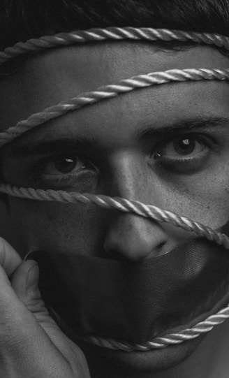 grayscale image of person tangled in rope with duct taped mouth