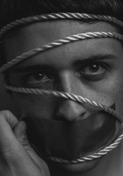 grayscale image of person tangled in rope with duct taped mouth