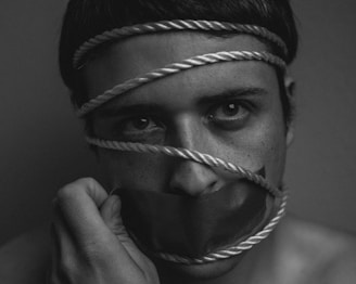 grayscale image of person tangled in rope with duct taped mouth