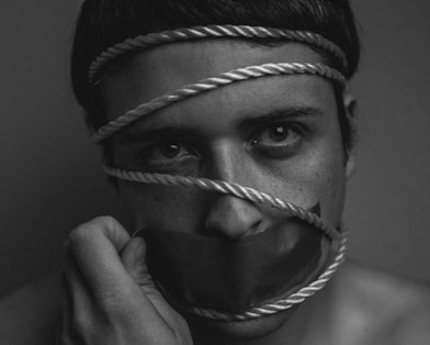grayscale image of person tangled in rope with duct taped mouth
