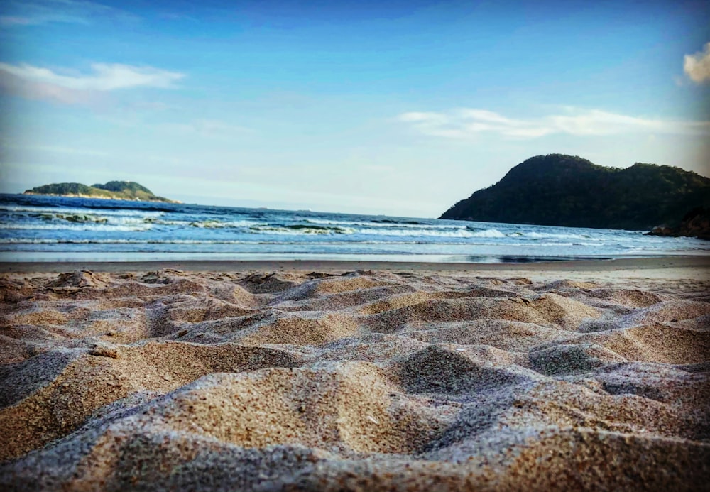 brauner Sandstrand mit blauem Meerwasser tagsüber