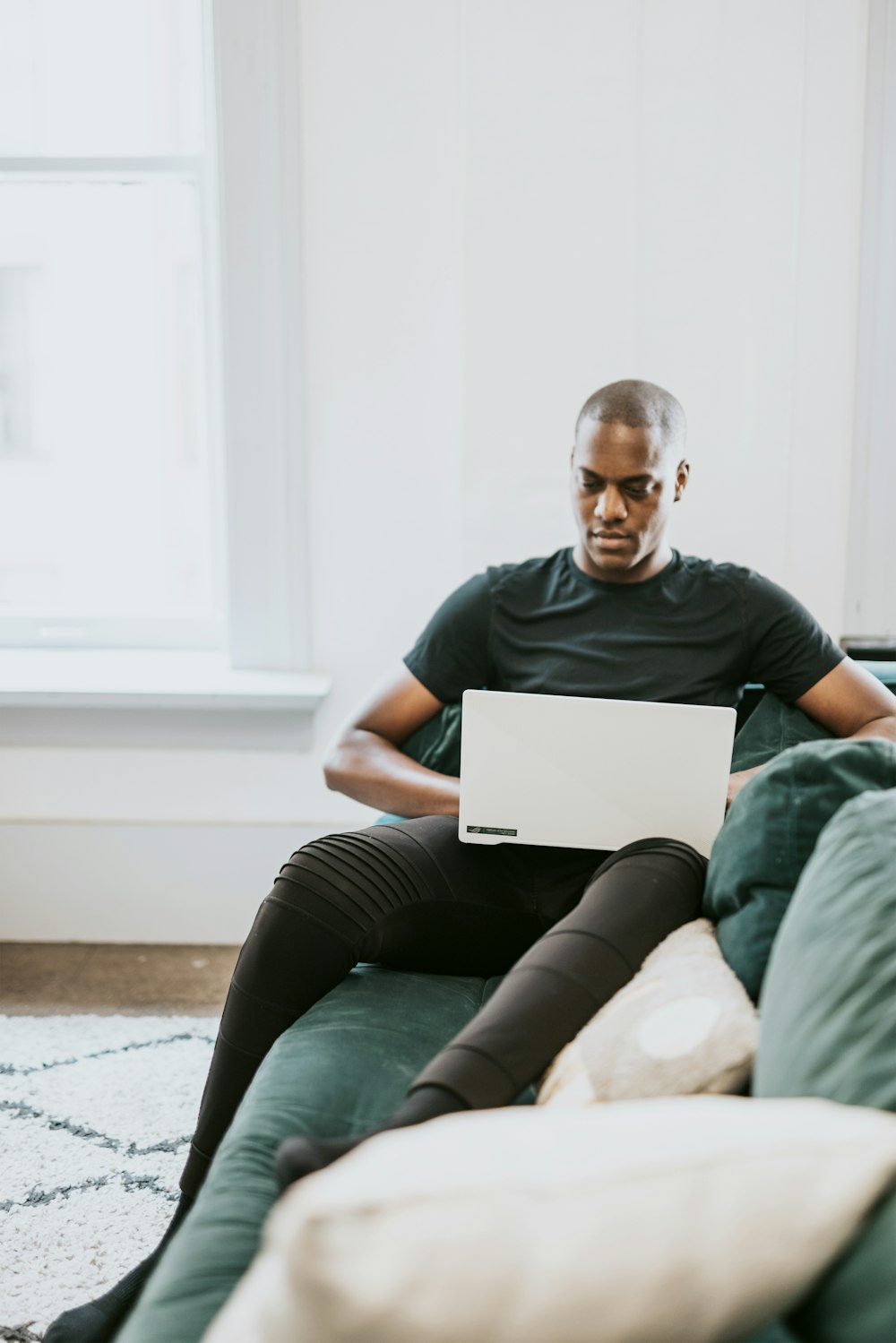 man in black crew neck t-shirt and black pants sitting on white couch