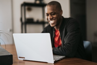 man in black blazer sitting by the table with laptop