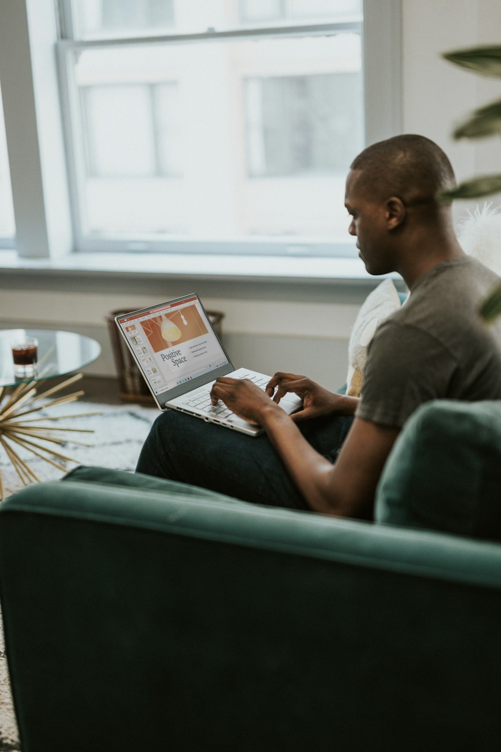 man in gray crew neck t-shirt sitting on couch using white tablet computer