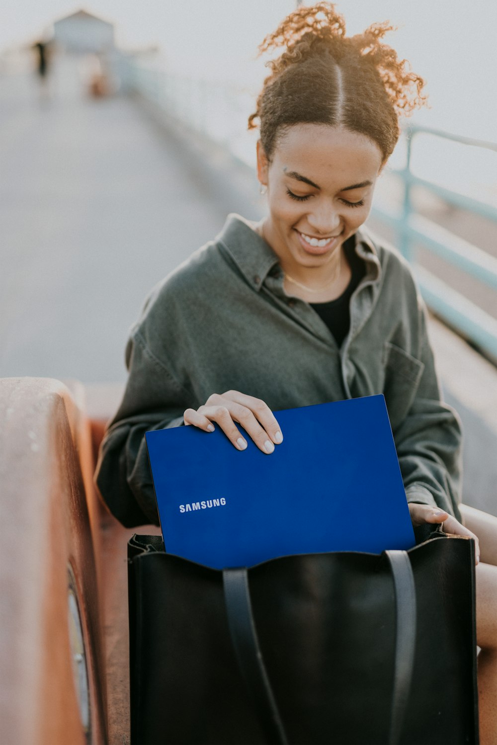 man in gray hoodie holding blue laptop