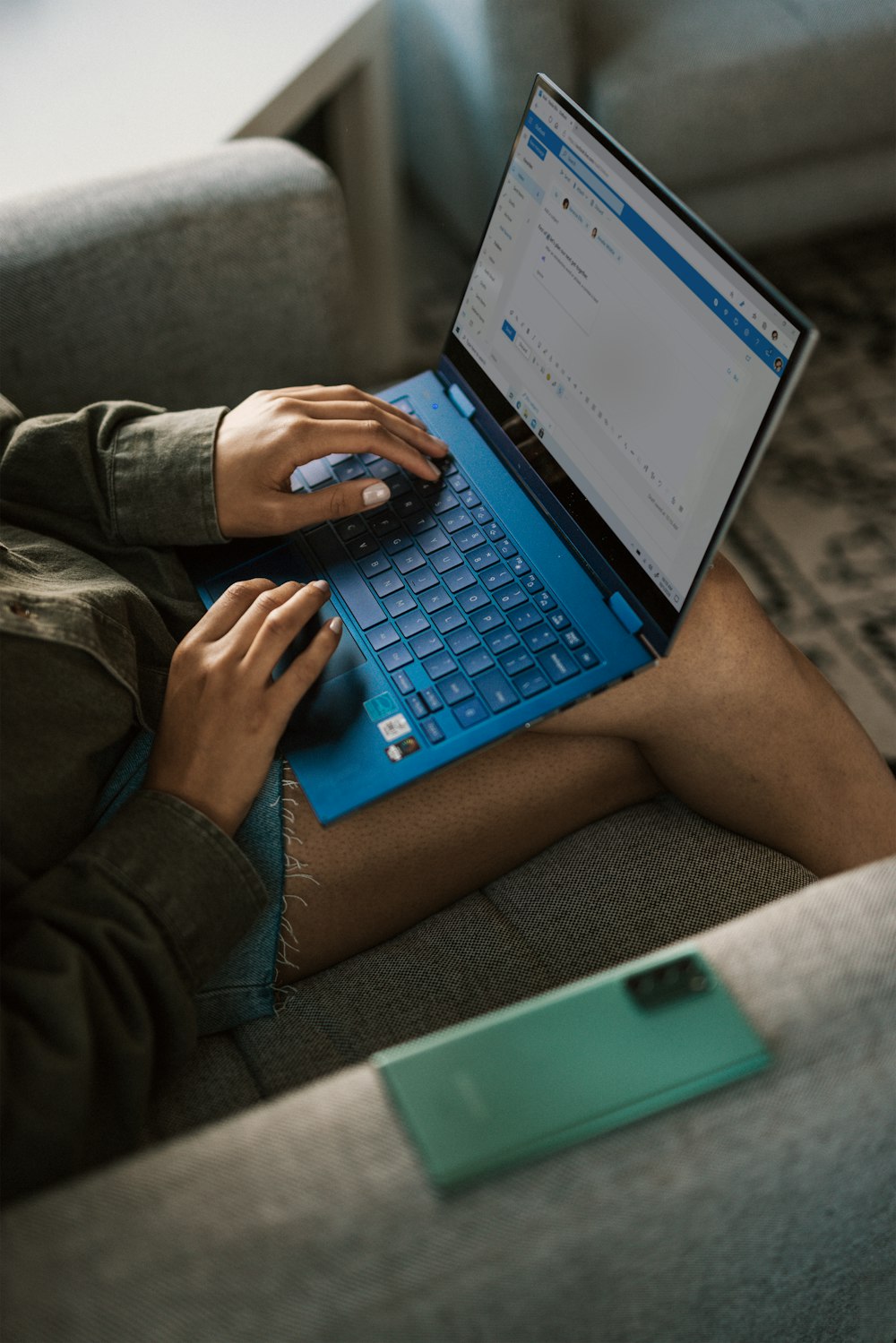 person in brown pants using blue laptop computer
